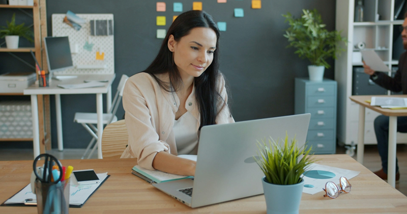 An employee working at her laptop in an open-plan office