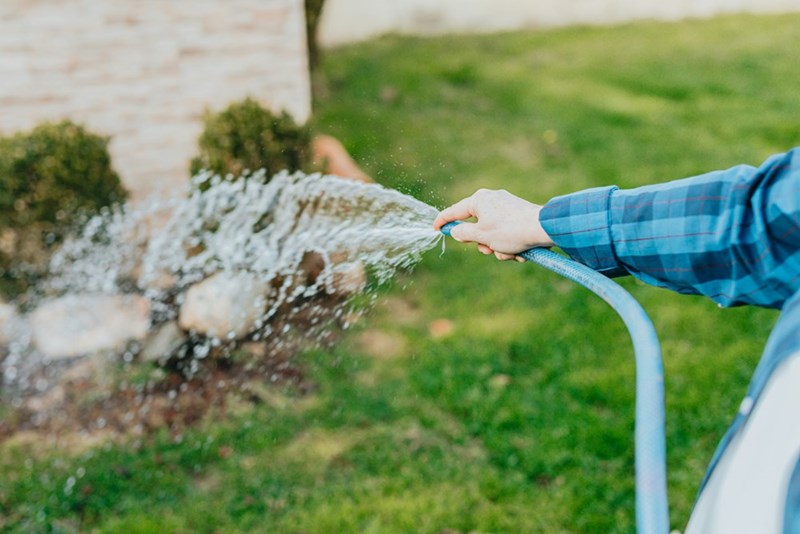 A man fills his pool in his back yard with a hose.