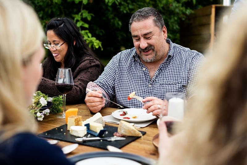 A man eating and sitting at a table outside, full of people.