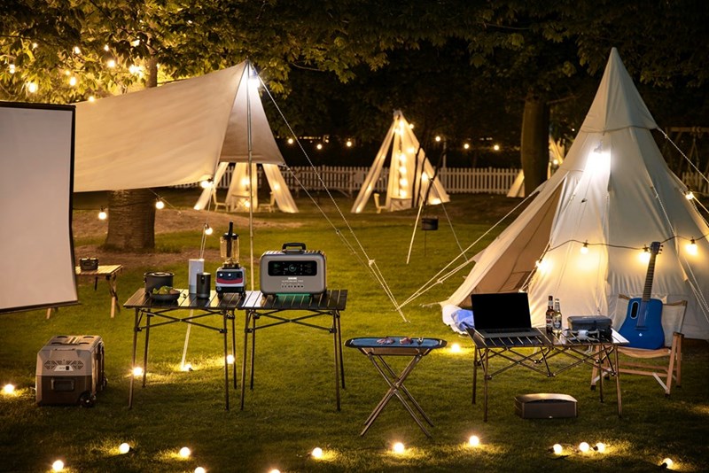 A group of white tents placed outside on green grass at night.