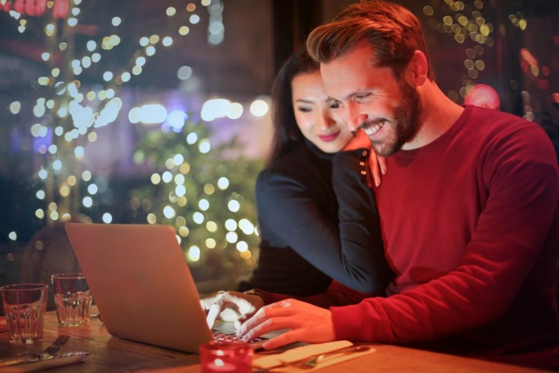 Couple looking at a silver laptop at night.