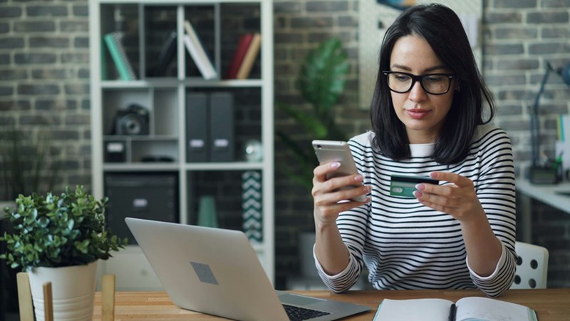 A woman using credit card information to buy something online. Model image.