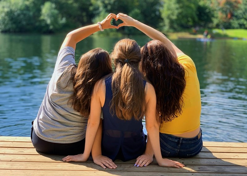 Young girls sitting by a lake at summer camp.