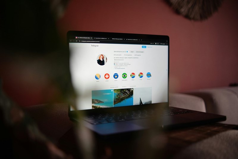 A silver computer sitting on a table with an Instagram account on the screen.