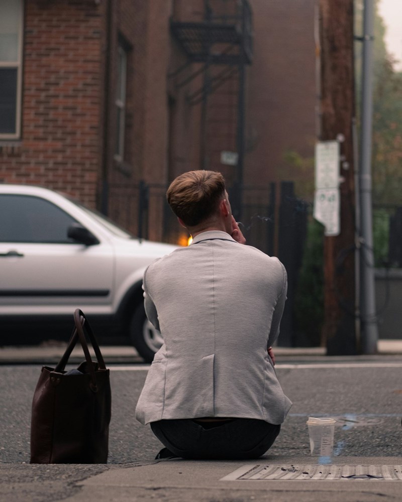 man in suit sitting on the curb