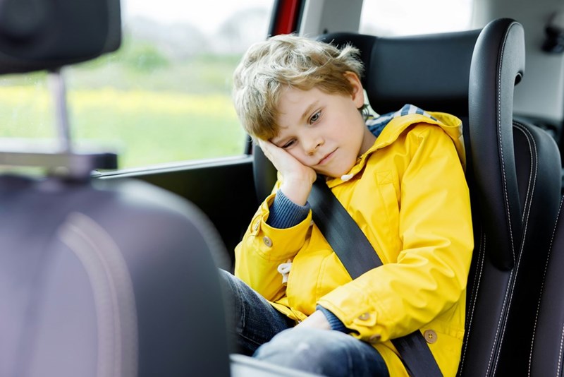 Young baseball player riding to a weekend game with sports gear and travel commitments ahead.