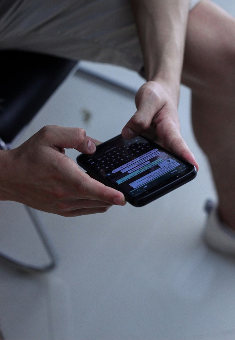 An employee holds a black phone with a work group chat pulled up