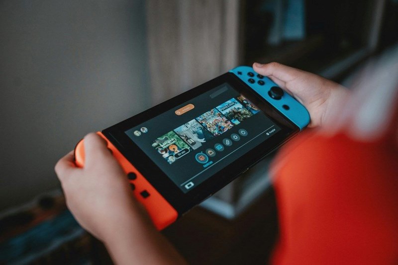 Person holding a blue-and-orange Nintendo Switch console while playing a video game.