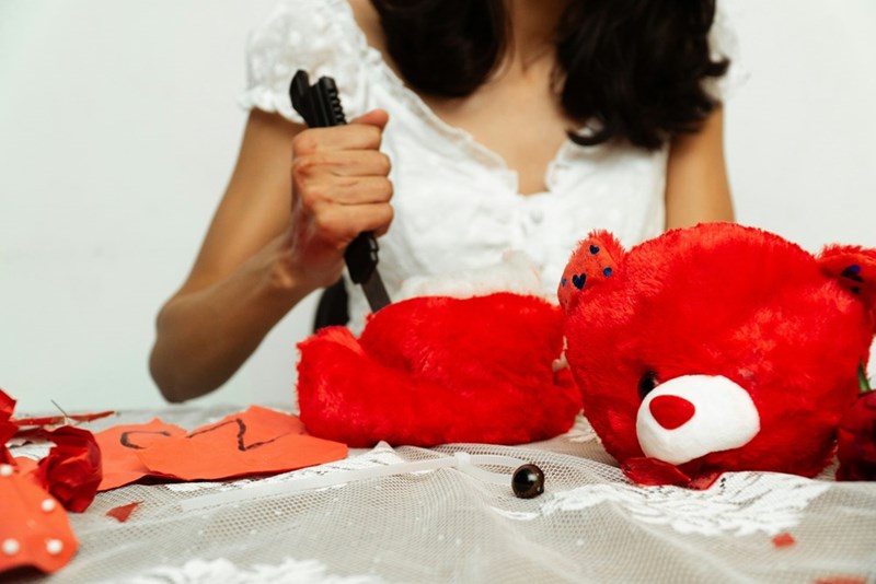 woman dismembers red teddy bear