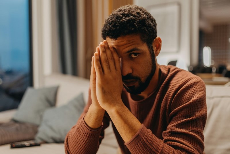 Man looking uneasy after an awkward reunion with an ex at a gathering with mutual friends.