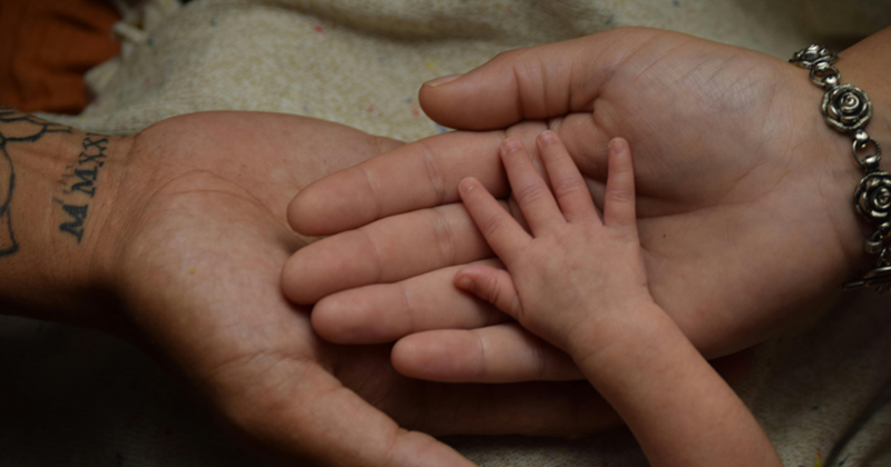 A child's hand resting on Mom and Dad's.