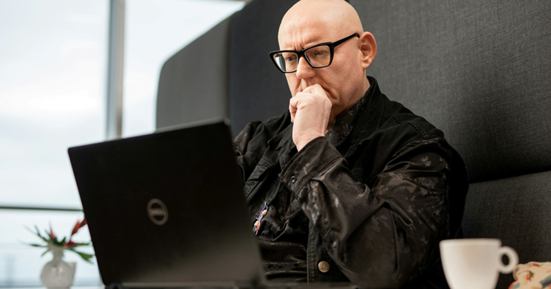 A representation of a middle-aged, glasses-wearing employee working on a laptop