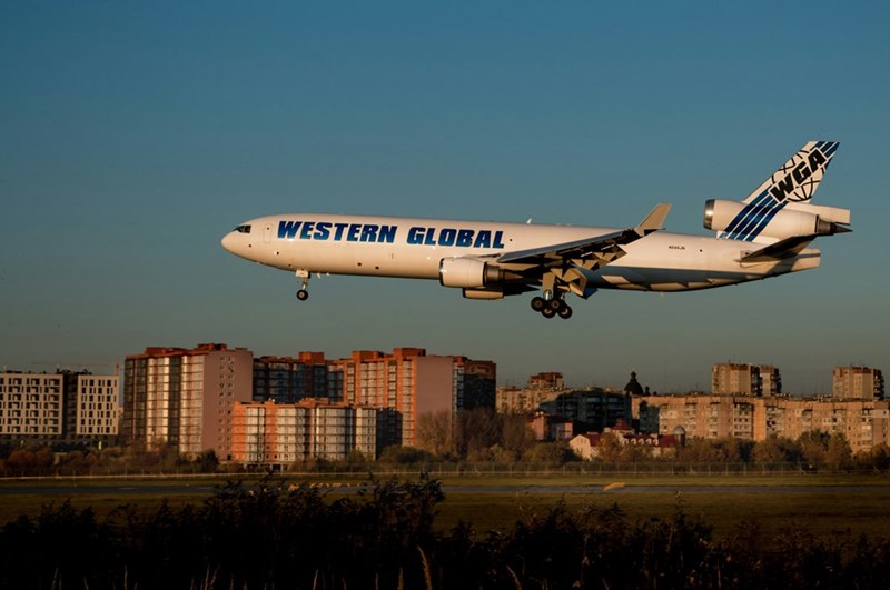 A big white plane overflying a city, model image.