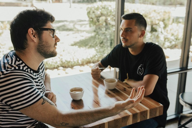 Two men having a conversation at a cafe.