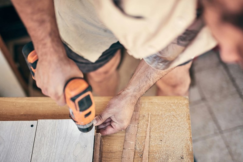 Contractor repairs a wooden fence during a residential property maintenance project involving shared fence repairs.