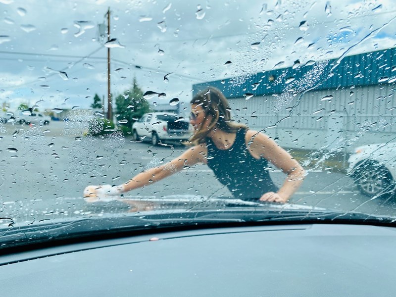 Young woman cleaning her car after complaining about being asked to handle basic adult responsibilities while staying with her boyfriend’s family.