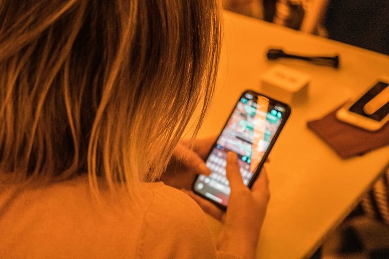 Woman with a white shirt texting over the phone.