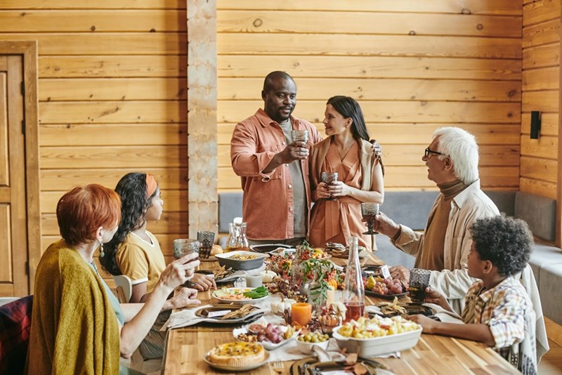 A large family sitting around a table full of food.