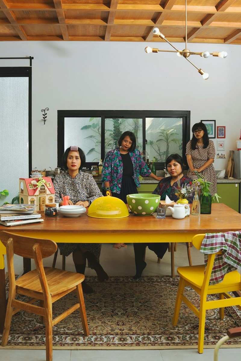 Four women gathered, sitting around a dinner table with dishes and empty chairs