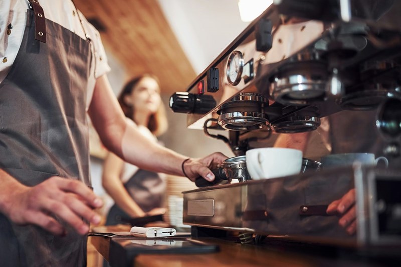 Two baristas making coffee in a shop.