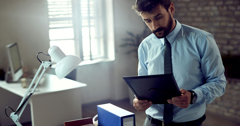 A male employee looking at a photo frame while standing in an office