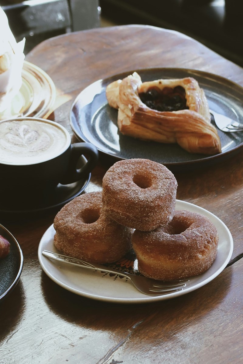 A cafe table full of delicious artisanal pastries and latte art.