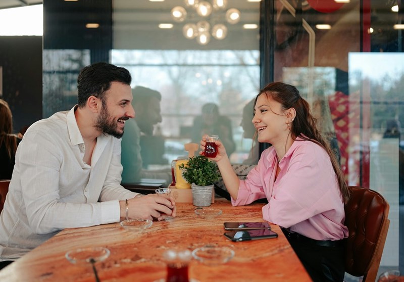 Two people on a date share a beverage at the table