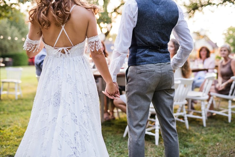 A bride and a groom from behind at an outdoor reception