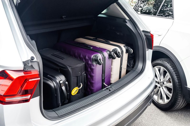 Open car trunk packed with a suitcase and luggage for an extended family vacation at a relative’s new home.