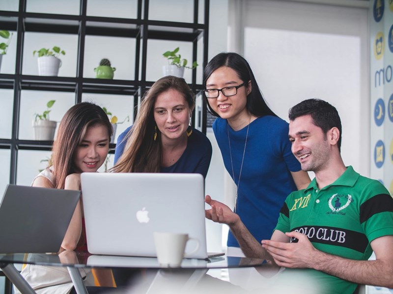 Coworkers looking at the screen of a computer and talking about it. Representation.