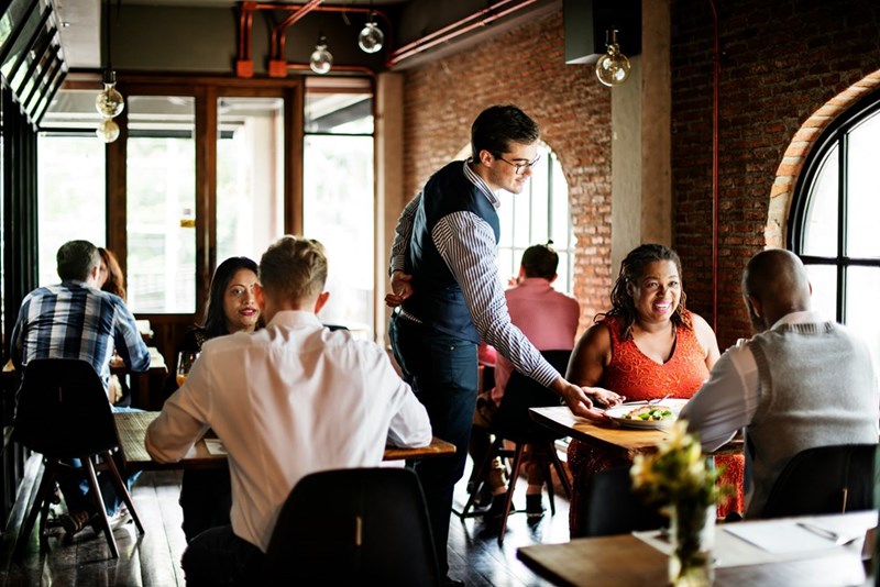 A waiter at a restaurant serves a plate to customers