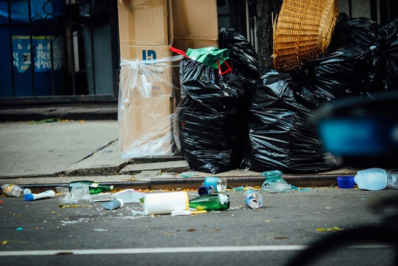 A street full of garbage, littered with garbage bags, visual representation.