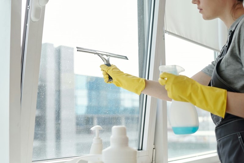 Hospital housekeeper cleaning windows during an early morning work shift.