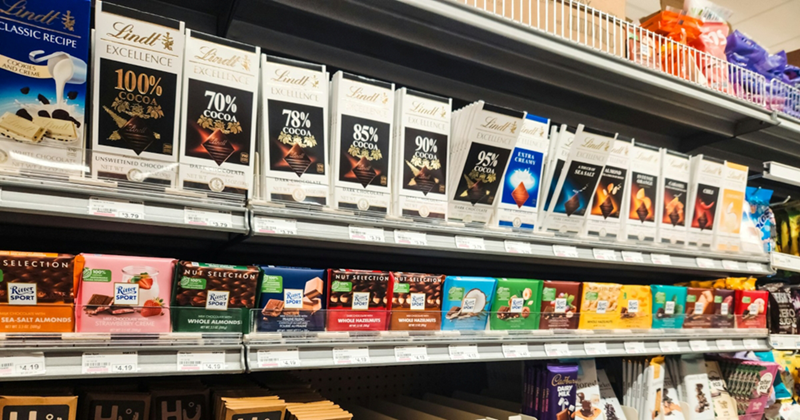 Grocery store shelves stocked with different brands of chocolate bars