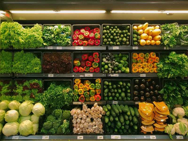 A grocery store aisle full of vegetables of different colors.