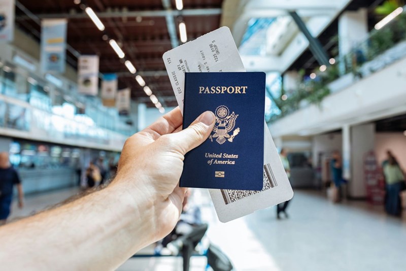 A person holding a passport and a boarding pass ticket in their hand.