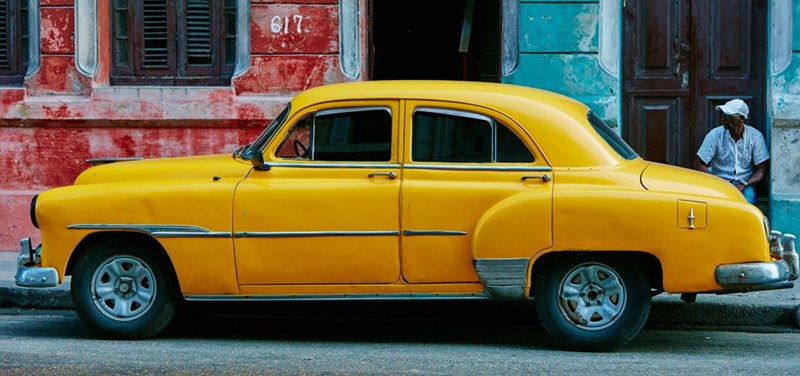 A yellow vintage car parked in the street.