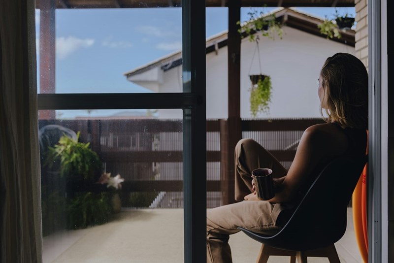 A woman contemplates while seated on the porch of her apartment unit