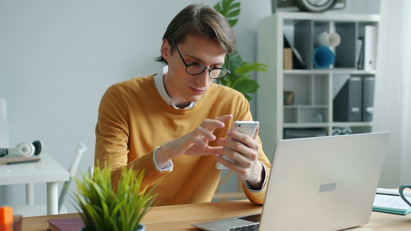 man in yellow sweater using phone