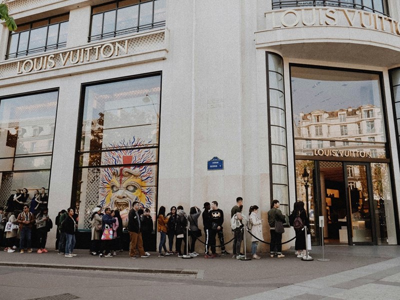 A long line outside of a big luxury store