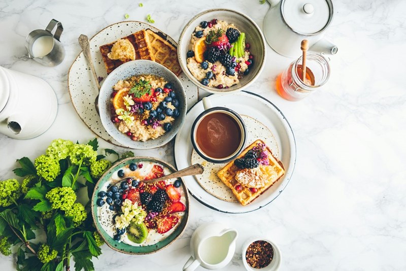 Breakfast set on different plates over a white tablecloth.