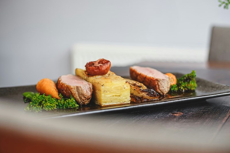 An entree placed over a dark plate at the table of a fancy restaurant.