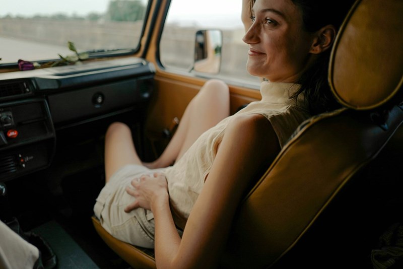 A woman sits in a car and looks out the window