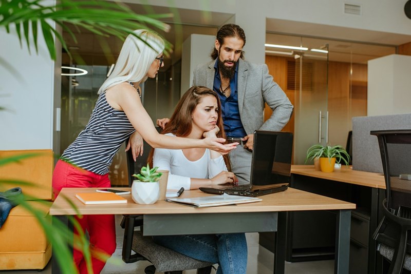 Overwhelmed employee listening as supervisors discuss new management responsibilities she never agreed to accept.