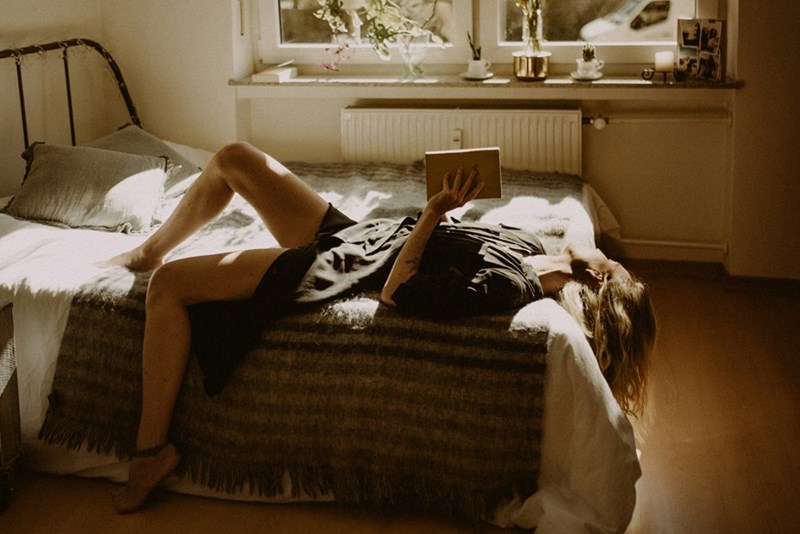 Adult daughter relaxing in her childhood bedroom after moving back into her parents' home during her work placement.