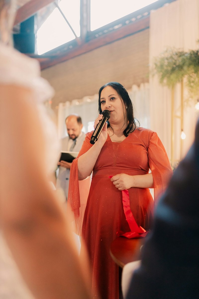 Aunt holding a microphone during a formal celebration, illustrating an attempted family toast at a wedding reception.