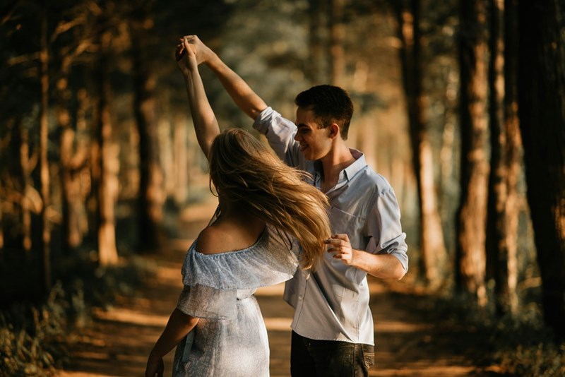 A couple of a man and a woman dancing together surrounded by trees. Representation.