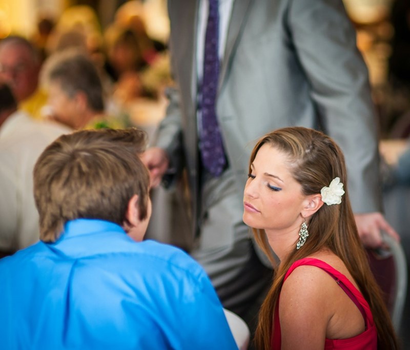 Older sister looks upset at her younger sister's wedding because she can't share the baby news with the relatives.