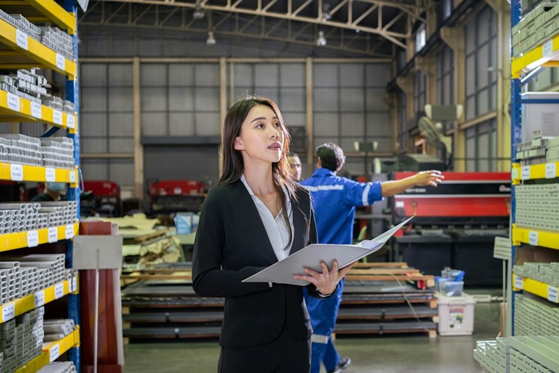 A worker in a warehouse looks at plans in front of her