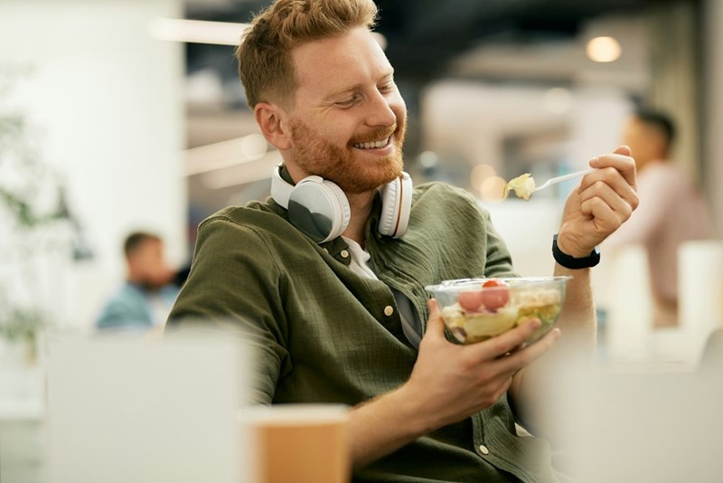 Employee holding a container filled with everyone's food, representing the coworker packing potluck leftovers to bring home after his shift.